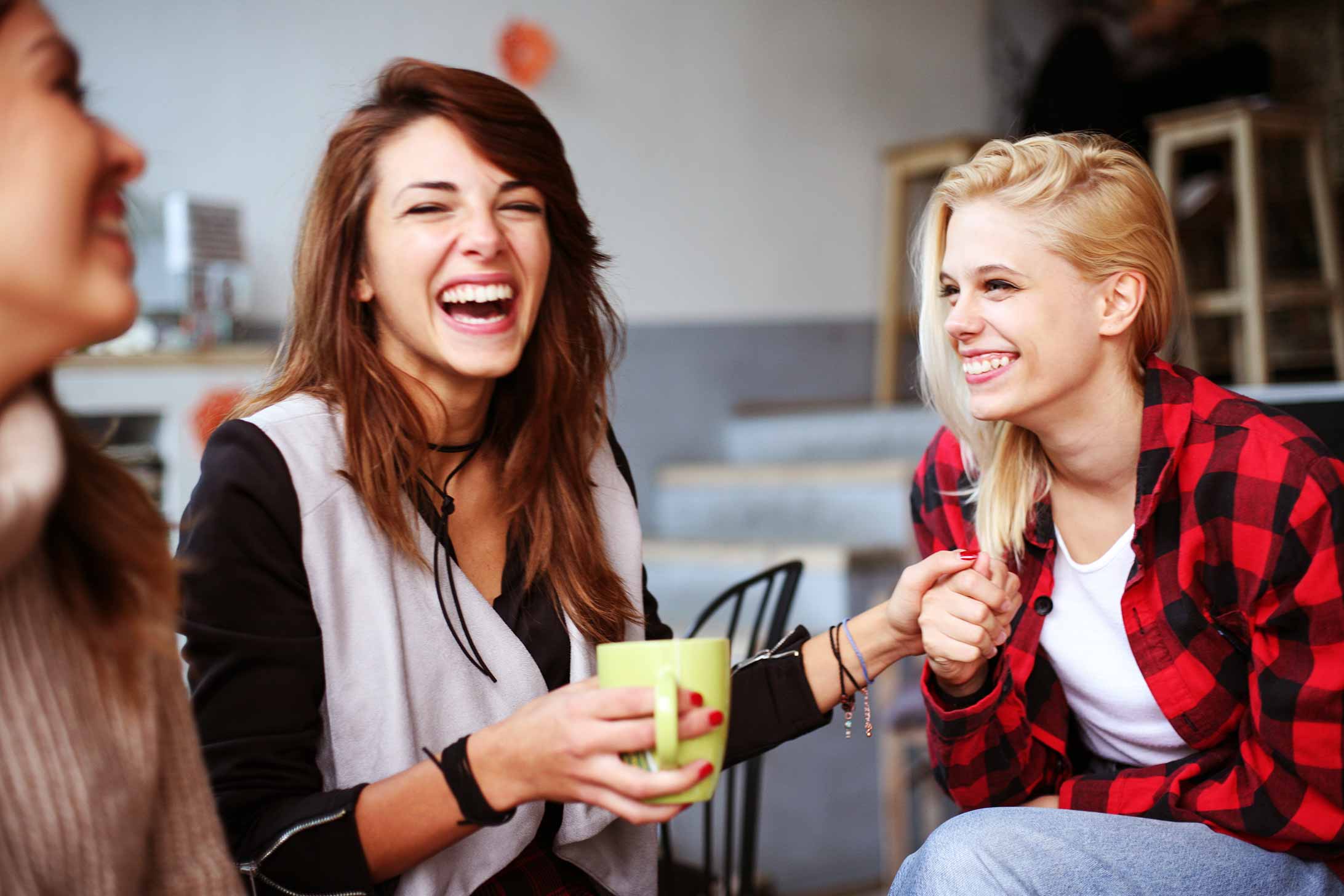 A group of people laughs and drinks coffee together during a meeting