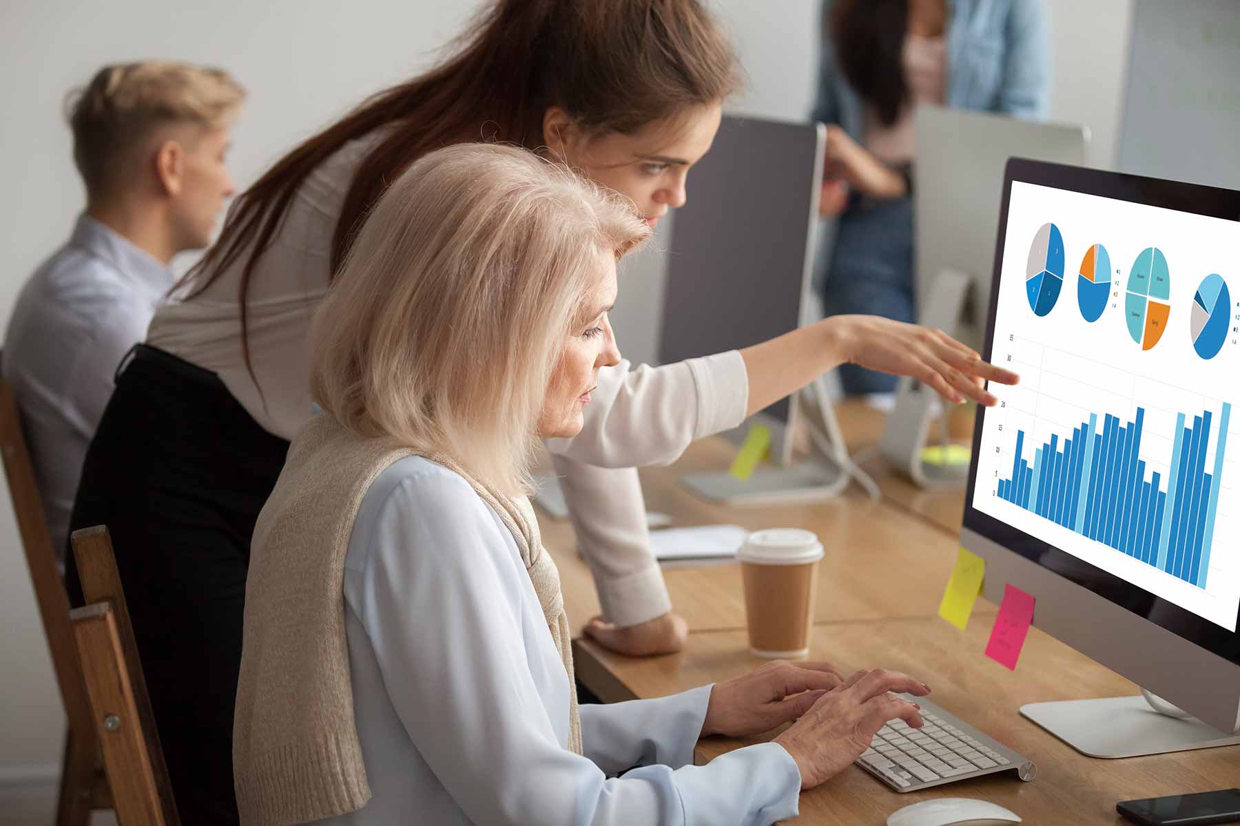 Young girl helps woman operate the PC